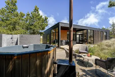 a modern house with a hot tub in the yard at Lovely Holiday Home With Outdoor Sauna And Wilderness Bath, Close To Klitmøller Center And The North Sea in Torsted