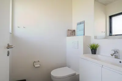 a white bathroom with a toilet and a sink at Lovely Holiday Home With Outdoor Sauna And Wilderness Bath, Close To Klitmøller Center And The North Sea in Torsted