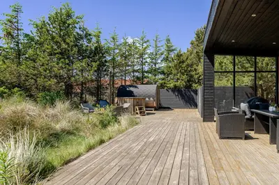 a wooden deck with chairs and tables on a house at Lovely Holiday Home With Outdoor Sauna And Wilderness Bath, Close To Klitmøller Center And The North Sea in Torsted