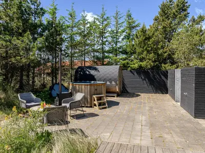 a patio with two chairs and a wooden table at Lovely Holiday Home With Outdoor Sauna And Wilderness Bath, Close To Klitmøller Center And The North Sea in Torsted