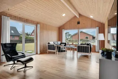 a living room with a table and chairs and windows at Lovely Holiday Home With Fenced Plot, 300 Meters From The North Sea In Thy in Lild Strand