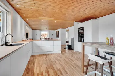a kitchen with white cabinets and a wooden ceiling at Lovely Holiday Home With Fenced Plot, 300 Meters From The North Sea In Thy in Lild Strand