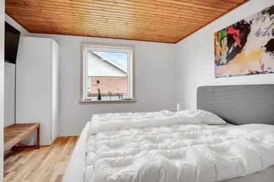 a white bedroom with a large bed and a window at Lovely Holiday Home With Fenced Plot, 300 Meters From The North Sea In Thy in Lild Strand