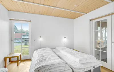 a white bedroom with a bed and a window at Holiday Home Spøttrup - 04 in Spottrup