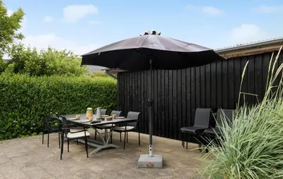 a table and chairs under an umbrella on a patio at Stunning Home In Blokhus With Wifi in Blokhus