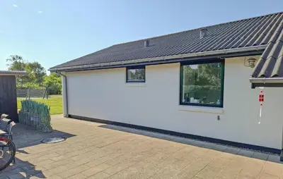 a white building with a black roof on a patio at Stunning Home In Blokhus With Wifi in Blokhus