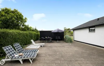 a patio with chairs and a table and an umbrella at Stunning Home In Blokhus With Wifi in Blokhus