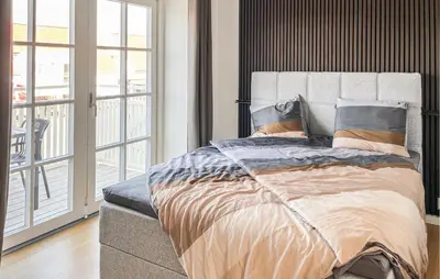 a bedroom with a large bed and a balcony at Cozy Apartment In Blokhus With Wifi in Blokhus