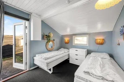 a bedroom with two beds and a window at Pirupshvarrevej 5A in Blokhus