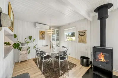 a dining room with a table and a fireplace at Pirupshvarrevej 5A in Blokhus