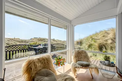a screened porch with two chairs and a view of the ocean at Forårsvangen 2 in Saltum