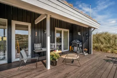 a deck with chairs and a grill on a house at Forårsvangen 2 in Saltum