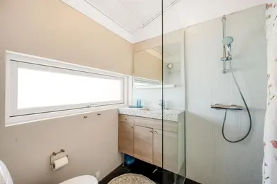 a bathroom with a shower and a toilet and a window at Forårsvangen 2 in Saltum