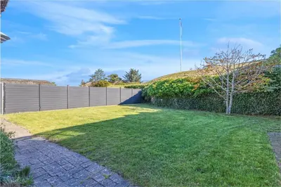 a backyard with a fence and a grass yard at 3008Møllehuset Baghusetanneks in Blokhus