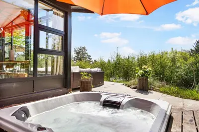 a bath tub with an umbrella on a patio at Granlien 3, A Holiday Home With Soul And Charm! in Blokhus