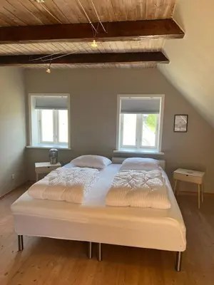 a large bed in a bedroom with two windows at VillaRanum in Ranum