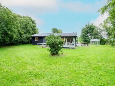 a small house in a field with a green yard at 6 person holiday home in Thyholm in Thyholm