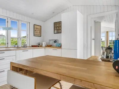 a kitchen with white cabinets and a wooden table at Holiday Home Thine - 250m from the sea by Interhome in Harboør