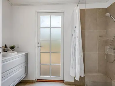 a bathroom with a shower and a glass door at Holiday Home Thine - 250m from the sea by Interhome in Harboør