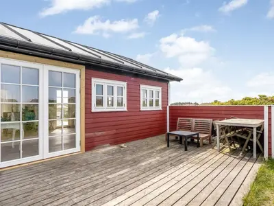 a red house with a picnic table on a deck at Holiday Home Thine - 250m from the sea by Interhome in Harboør