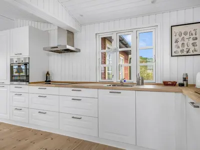 a white kitchen with white cabinets and a window at Holiday Home Thine - 250m from the sea by Interhome in Harboør