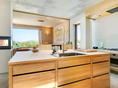 a kitchen with wooden cabinets and a large window at Holiday Home Rieke - 250m from the sea by Interhome in Torsted