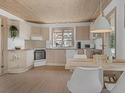 a kitchen with white cabinets and a table and chairs at Holiday Home Antine - 400m from the sea by Interhome in Thyborøn