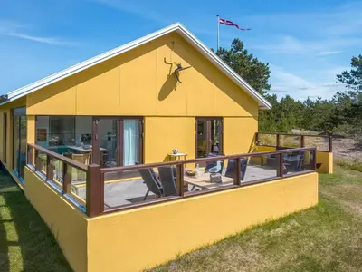 a yellow house with a large deck at Holiday Home Ola - 900m from the sea by Interhome in Bedsted Thy