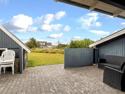 a patio with a white chair and a couch at Holiday Home Claudine - 700m from the sea by Interhome in Thisted