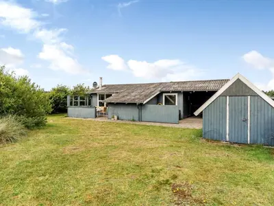 a house with a blue barn and a yard at Holiday Home Claudine - 700m from the sea by Interhome in Thisted