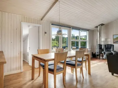 a dining room with a wooden table and chairs at Holiday Home Claudine - 700m from the sea by Interhome in Thisted