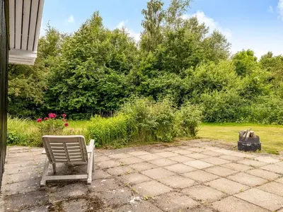 a chair sitting on a patio in a yard at Holiday Home Ginette - 400m to the fjord by Interhome in Åbybro