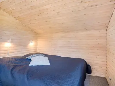 a bedroom with a bed in a wooden room at Holiday Home Laris - 700m to the fjord by Interhome in Løgsted