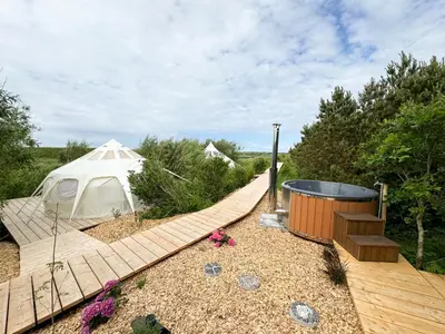 a white tent and a wooden walkway with a wooden deck at Agger Glamping - Lyngheden in Vestervig