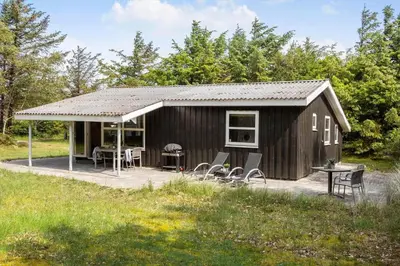 a black shed with chairs and a table in a field at 1067-Thisted-Gra-Rimme-7 in Torsted