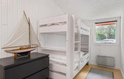 a bedroom with two bunk beds and a boat on a dresser at 3 Bedroom Amazing Home In Aabybro in Åbybro