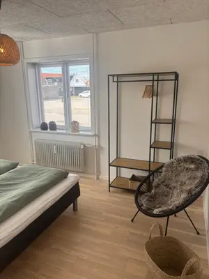 a room with a bed and a chair and a window at Ny lækker lejlighed på Havnen in Thyborøn