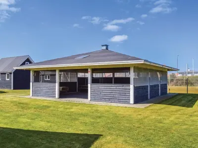 a house with a porch with a grass yard at 4 star holiday home in Thyborøn in Thyborøn