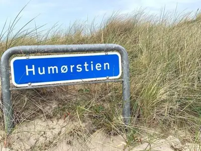 a blue street sign sitting in the sand at 4 star holiday home in Thyborøn in Thyborøn