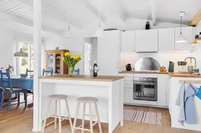 a kitchen with white cabinets and a counter with stools at 399-Thisted-Sotungevej-21 in Nørre Vorupør