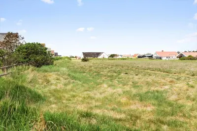 a field of grass with houses in the background at 421-Thisted-Fiskervej-147 in Nørre Vorupør
