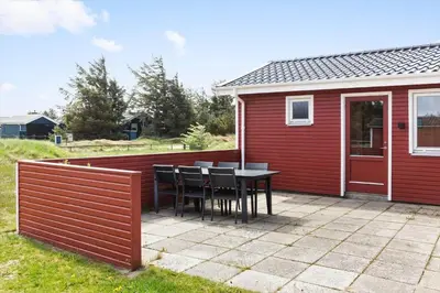 a patio with a table and chairs next to a red building at 421-Thisted-Fiskervej-147 in Nørre Vorupør