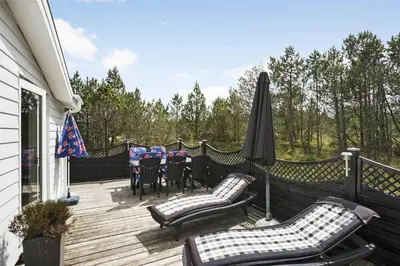 a deck with chairs and tables and an umbrella at 880-Thisted-Havtornvej-4 in Thisted