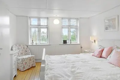 a bedroom with a bed and a chair and windows at 872-Bedsted-Thy-Lyngbyvej-25 in Bedsted Thy