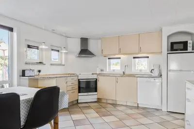 a kitchen with white appliances and a table with chairs at 1046-Thisted-Johns-Vej-26 in Torsted