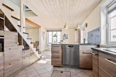 a large kitchen with wooden cabinets and a staircase at 823-Thisted-Knottivej-3 in Thisted