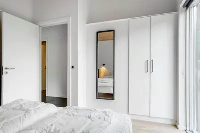 a white bedroom with a bed and a mirror at 454-Thisted-Havbovej-36 in Thisted