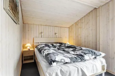 a bedroom with a bed and a wooden wall at 705-Thisted-Klitrosevej-22 in Thisted