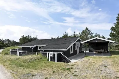 a black house with a porch on a hill at 705-Thisted-Klitrosevej-22 in Thisted