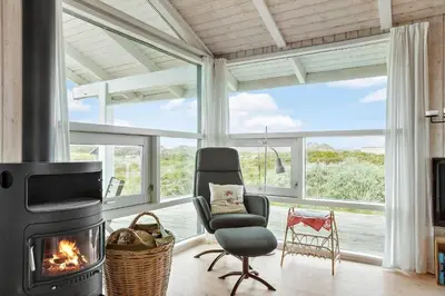 a living room with a fireplace and a chair at 334-Snedsted-Somaerkevej-64-B in Snedsted